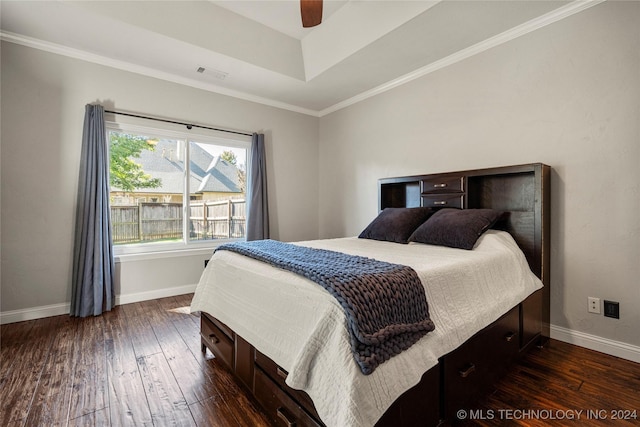 bedroom with ceiling fan, dark wood-type flooring, a raised ceiling, and crown molding