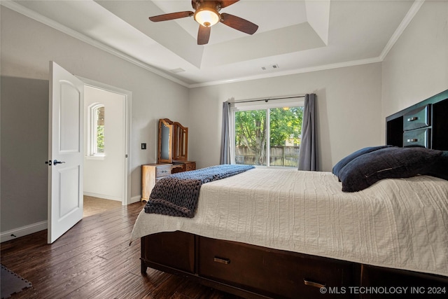 bedroom with dark wood-style flooring, visible vents, baseboards, a tray ceiling, and crown molding