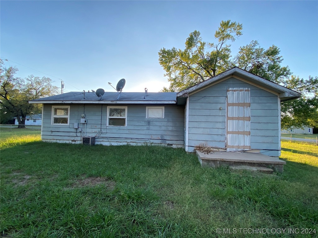 rear view of property featuring central AC unit, a shed, and a yard