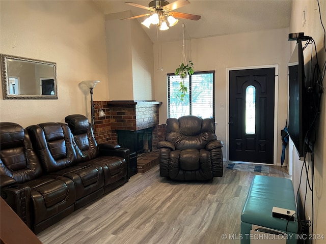 living room with a brick fireplace, wood-type flooring, ceiling fan, and a textured ceiling