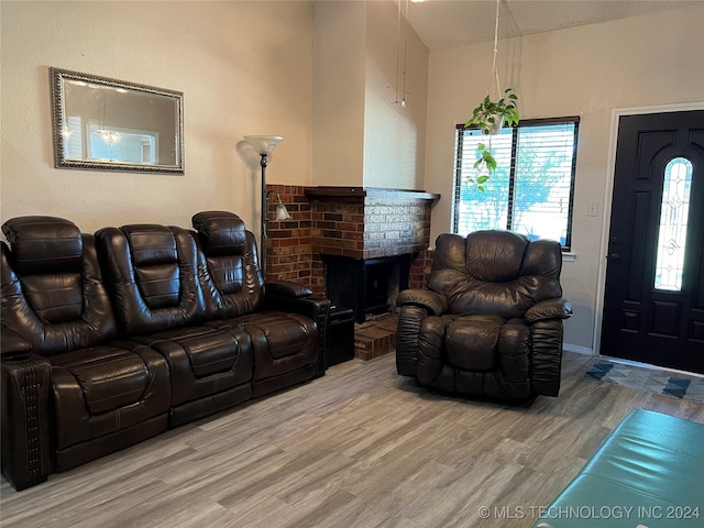 living room featuring wood-type flooring and a brick fireplace