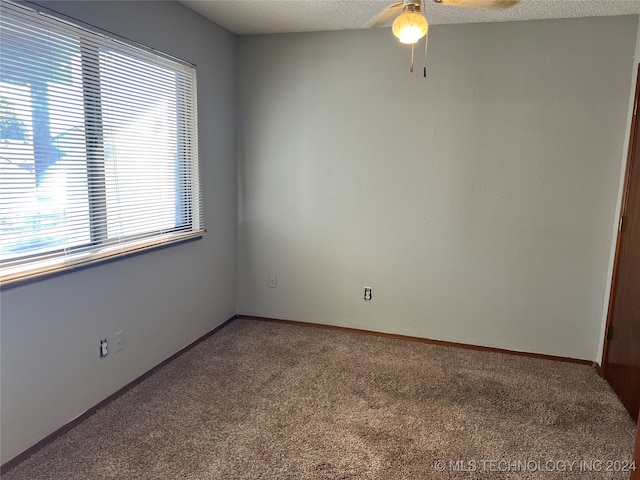 carpeted spare room featuring ceiling fan and a textured ceiling