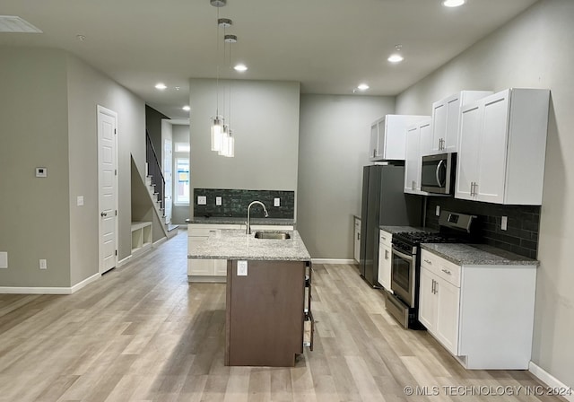 kitchen with light stone counters, appliances with stainless steel finishes, hanging light fixtures, and sink