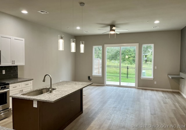 kitchen with white cabinetry, light stone countertops, ceiling fan, decorative light fixtures, and sink