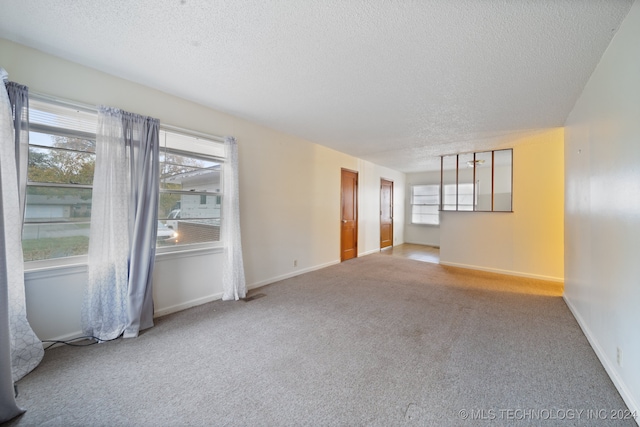 carpeted empty room with a textured ceiling