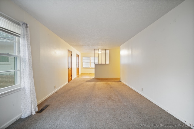 carpeted spare room with a healthy amount of sunlight and a textured ceiling