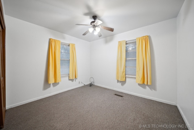 empty room featuring dark colored carpet and ceiling fan