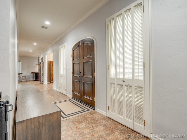 tiled entryway featuring plenty of natural light and ornamental molding