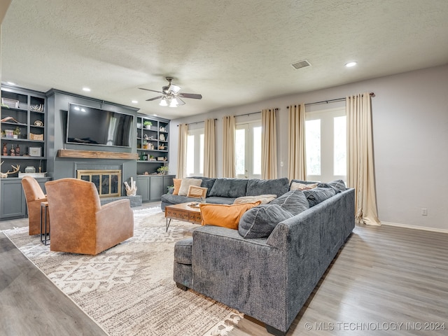 living room with ceiling fan, a textured ceiling, and wood-type flooring