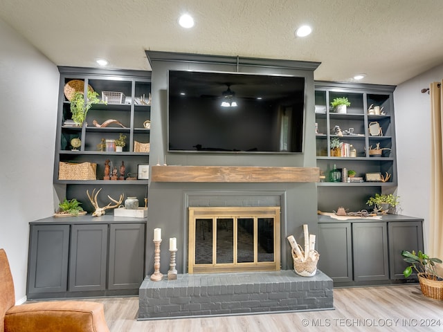 living room with light hardwood / wood-style floors, a textured ceiling, and a fireplace