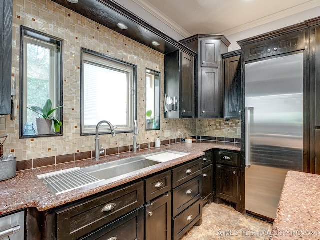 kitchen with stainless steel built in fridge, dark brown cabinetry, sink, backsplash, and crown molding