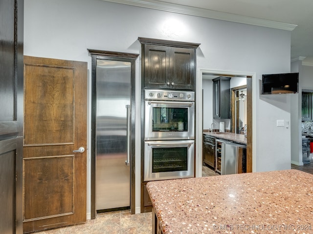 kitchen featuring light stone counters, dark brown cabinets, stainless steel appliances, and ornamental molding