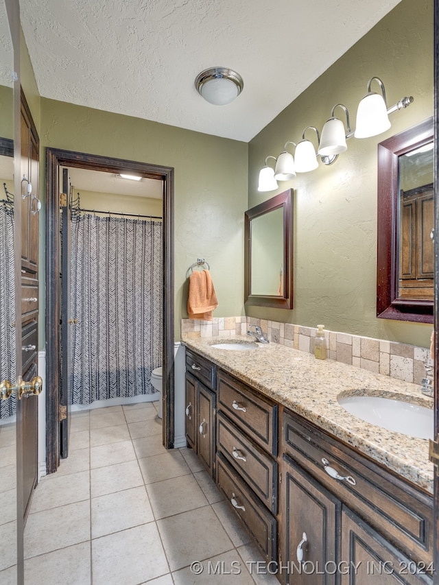 bathroom featuring a textured ceiling, walk in shower, tile patterned floors, vanity, and toilet