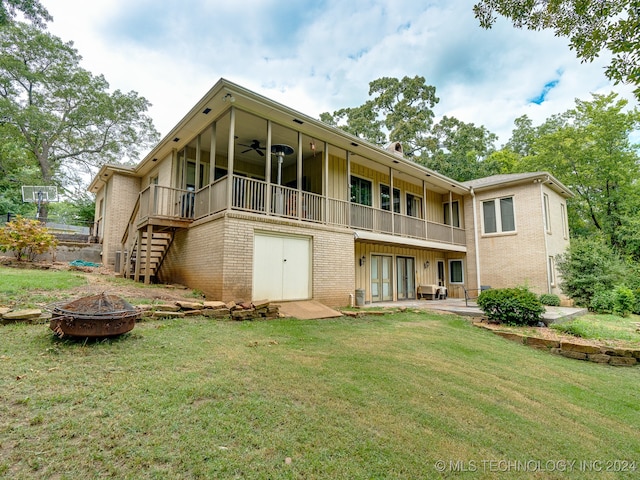 back of property with ceiling fan, a patio, a balcony, a lawn, and an outdoor fire pit