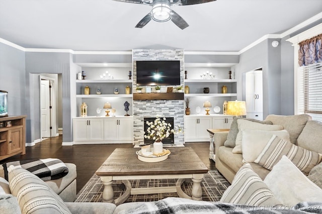 living room featuring built in shelves, dark hardwood / wood-style flooring, a fireplace, and crown molding