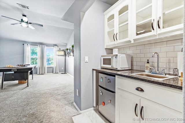 kitchen with white cabinets, refrigerator, sink, and tasteful backsplash