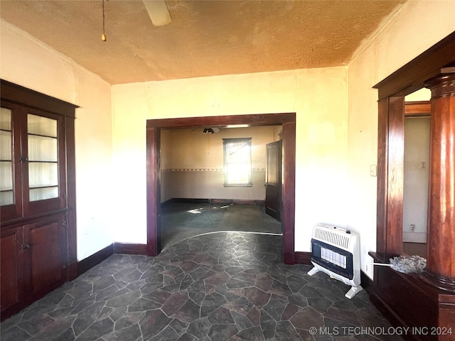 corridor with heating unit, a textured ceiling, and decorative columns