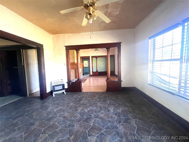 interior space with heating unit, decorative columns, and ceiling fan