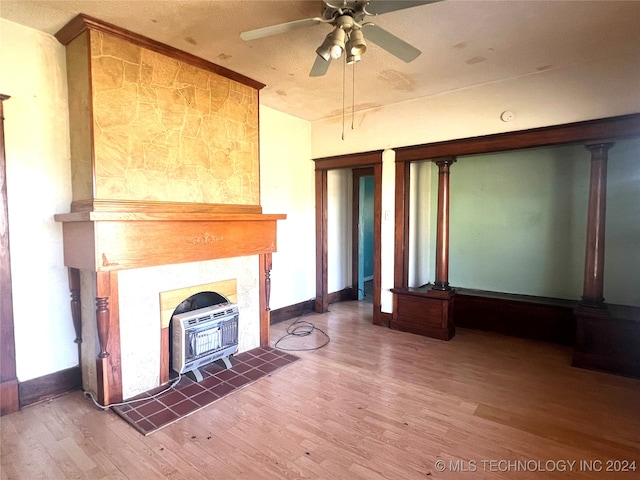 unfurnished living room featuring heating unit, a wood stove, ceiling fan, and hardwood / wood-style floors