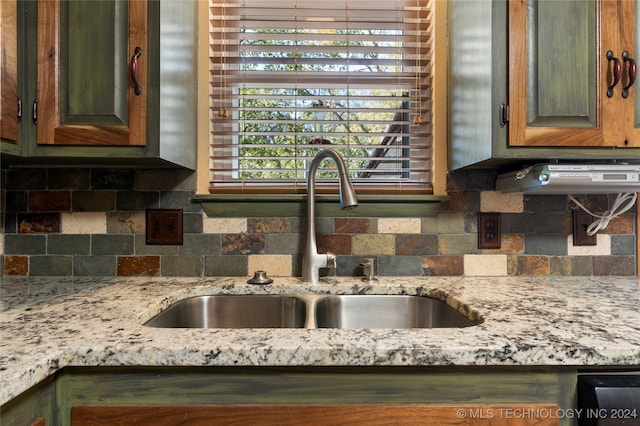 kitchen featuring decorative backsplash, sink, and light stone counters