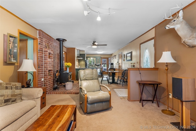 carpeted living room featuring a wood stove, ceiling fan, and crown molding