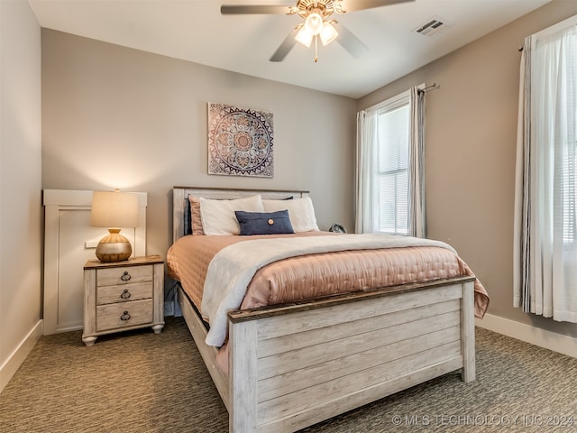 carpeted bedroom featuring multiple windows and ceiling fan