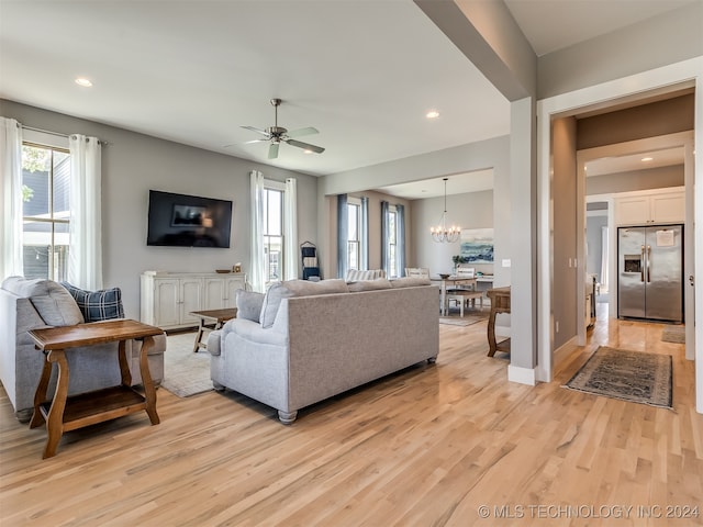 living room featuring ceiling fan with notable chandelier and light hardwood / wood-style floors