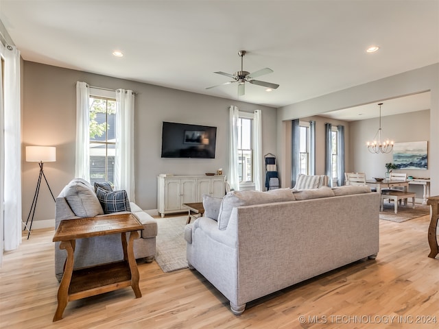 living room featuring ceiling fan with notable chandelier and light wood-type flooring