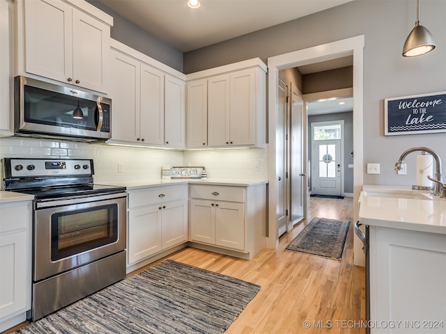 kitchen featuring decorative backsplash, light wood-type flooring, sink, stainless steel appliances, and white cabinetry