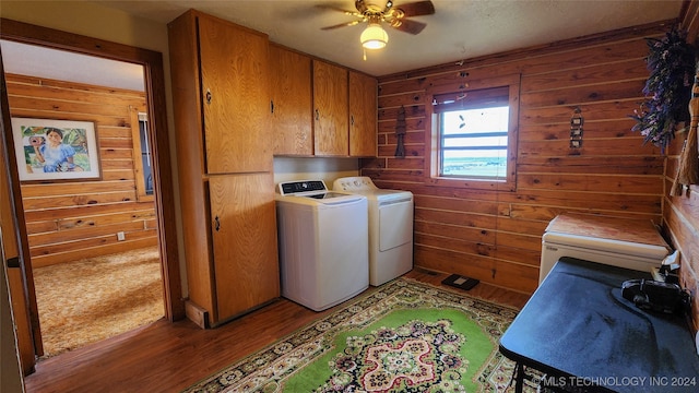 laundry area with light hardwood / wood-style flooring, ceiling fan, cabinets, wooden walls, and washer and dryer