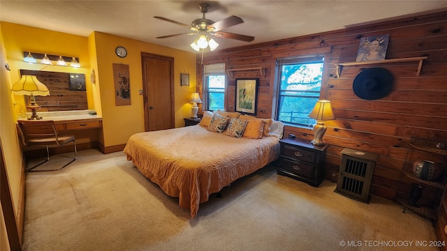 carpeted bedroom with ceiling fan and wood walls