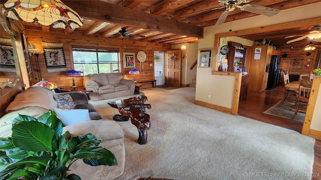 living room with wooden walls, beam ceiling, hardwood / wood-style floors, and ceiling fan