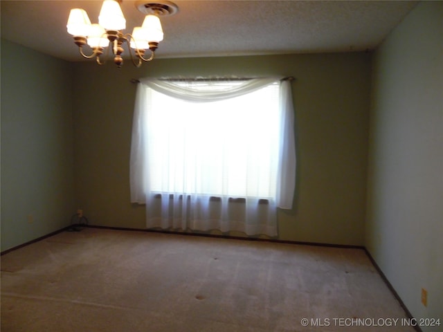 carpeted empty room with a notable chandelier