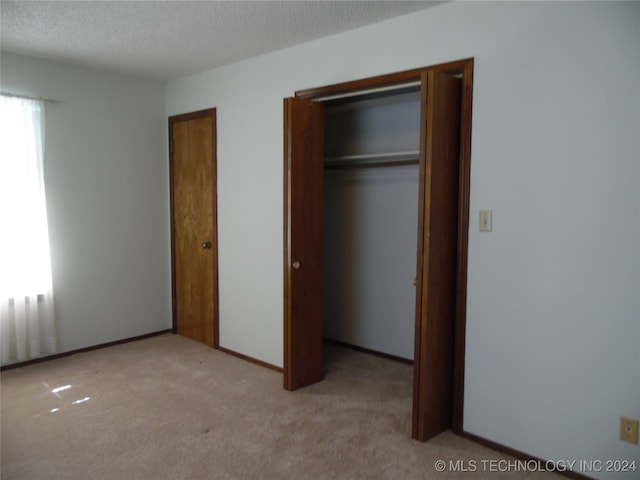 unfurnished bedroom with light carpet and a textured ceiling