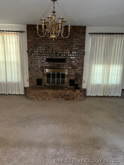 unfurnished living room featuring carpet floors, a textured ceiling, a fireplace, and a notable chandelier