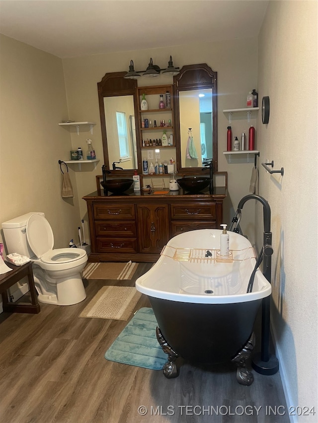 bathroom featuring toilet, hardwood / wood-style flooring, sink, and a tub to relax in