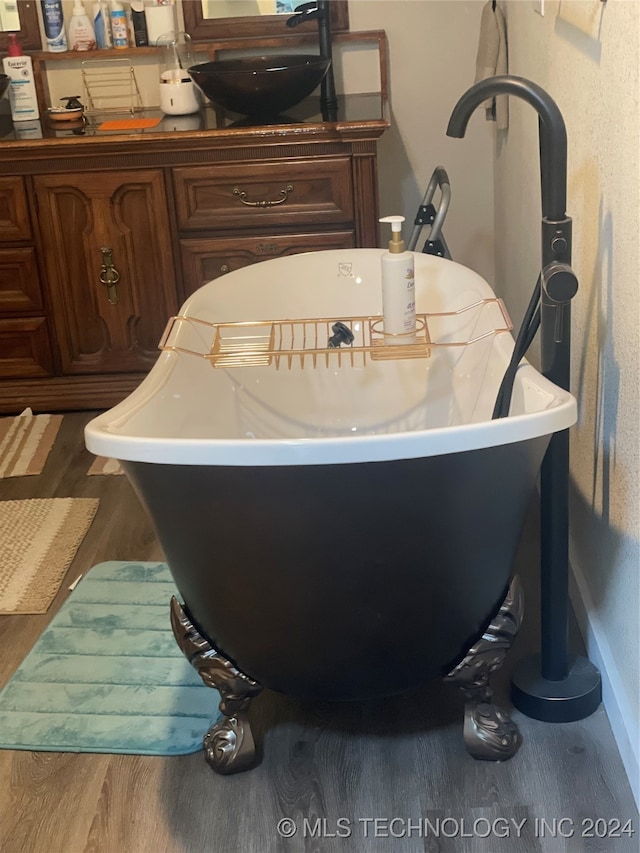 interior details featuring a bath, hardwood / wood-style flooring, and sink