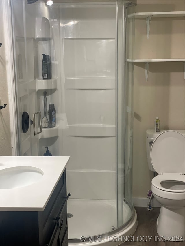 bathroom with walk in shower, vanity, and toilet