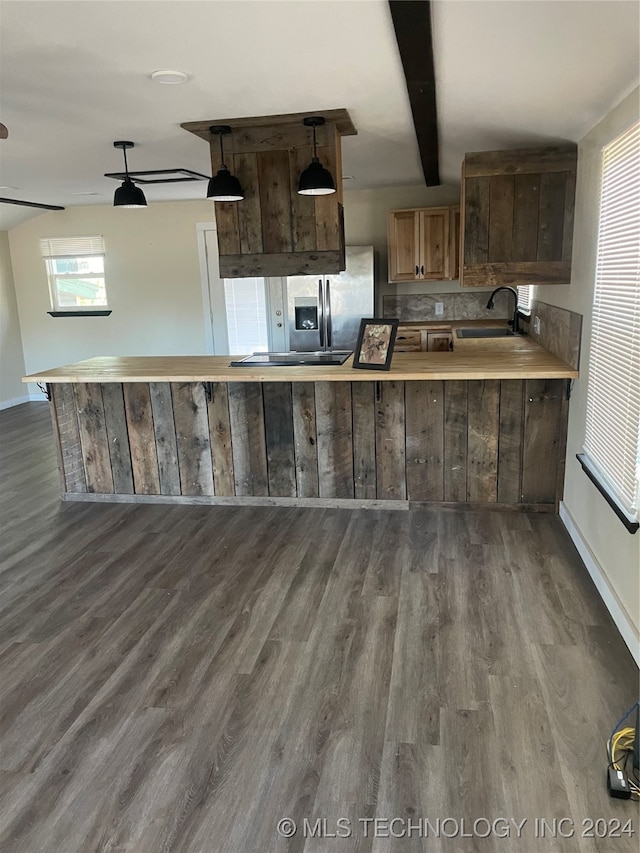 kitchen featuring dark hardwood / wood-style flooring, kitchen peninsula, a healthy amount of sunlight, and hanging light fixtures