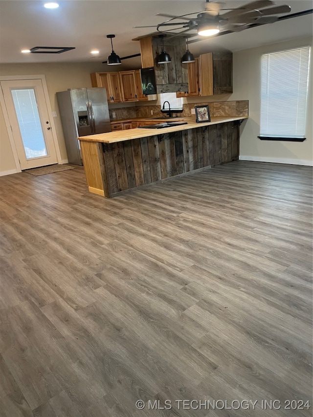 kitchen featuring hanging light fixtures, light hardwood / wood-style floors, stainless steel fridge, and kitchen peninsula