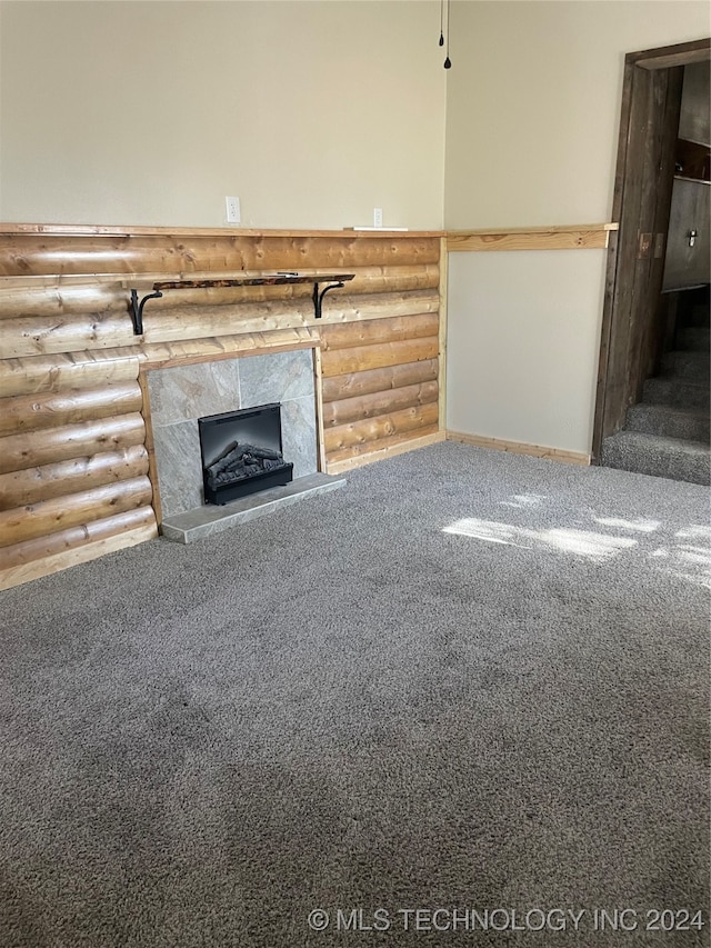 unfurnished living room with rustic walls, carpet flooring, and a tile fireplace