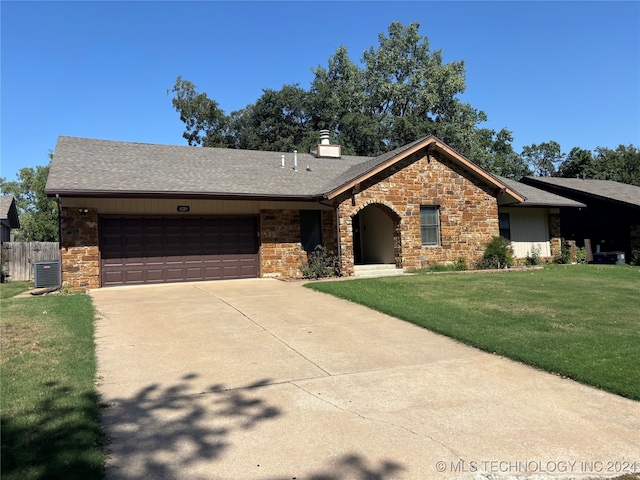 ranch-style house featuring a front yard, central air condition unit, and a garage