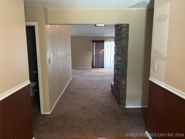 hall with carpet floors and a textured ceiling