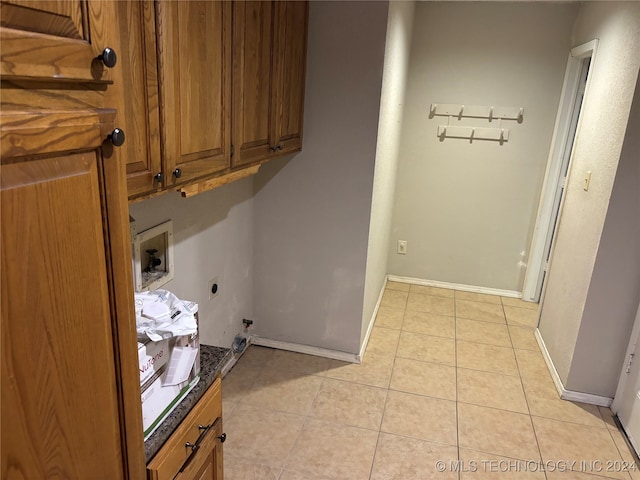 washroom with hookup for a washing machine, cabinets, light tile patterned floors, and hookup for an electric dryer