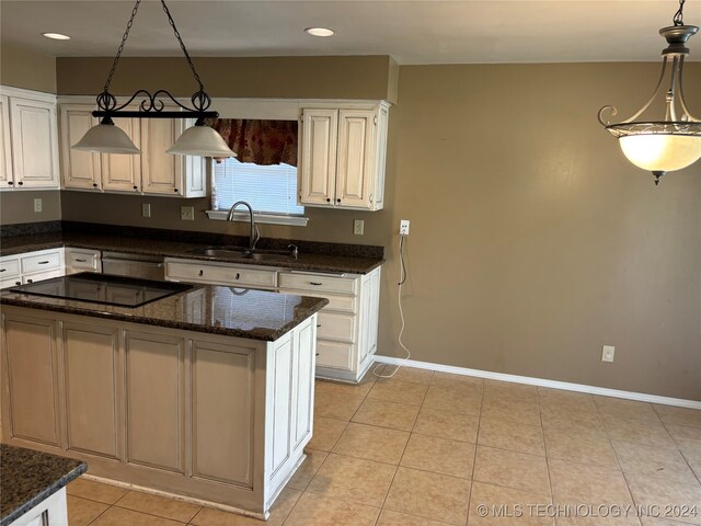 kitchen featuring pendant lighting, sink, a kitchen island, white cabinetry, and dark stone counters