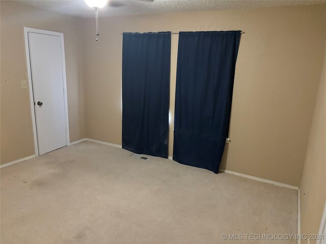 carpeted empty room featuring ceiling fan and a textured ceiling