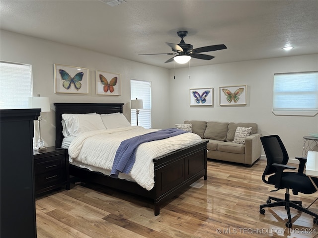 bedroom with ceiling fan, a textured ceiling, and light hardwood / wood-style flooring