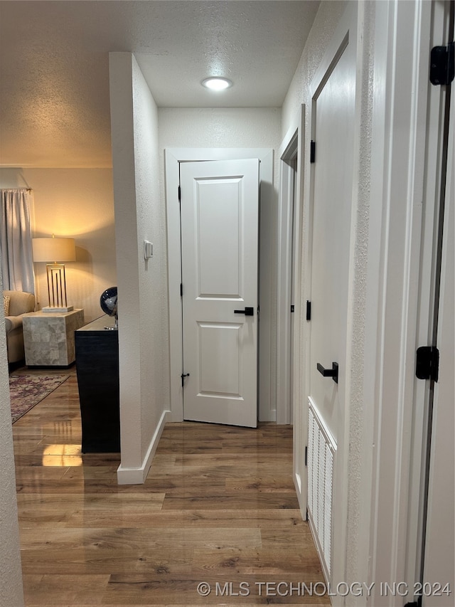 corridor featuring light hardwood / wood-style floors and a textured ceiling