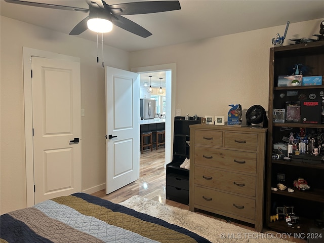 bedroom featuring stainless steel fridge, ensuite bathroom, ceiling fan, and light hardwood / wood-style floors