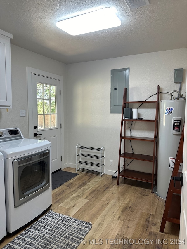 laundry area featuring water heater, electric panel, light hardwood / wood-style flooring, washing machine and dryer, and a textured ceiling